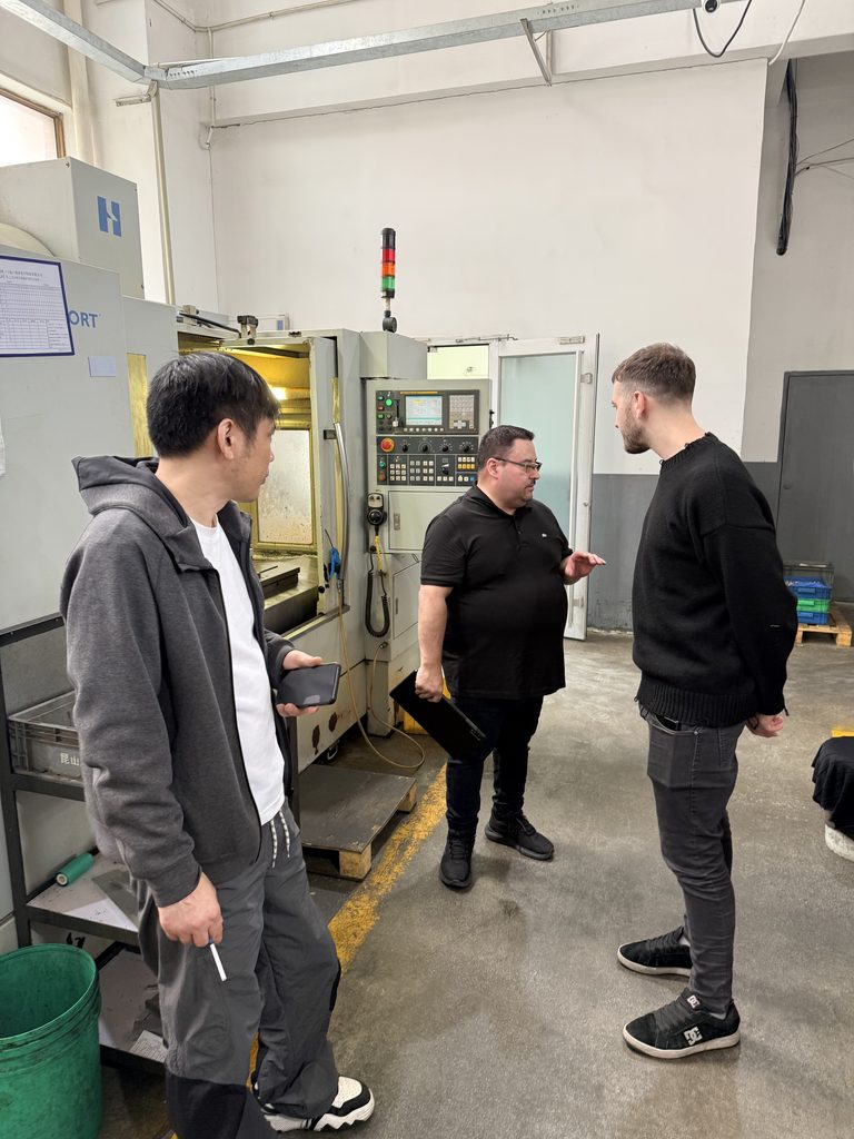 Visitors and Jinxi staff discussing a CNC machine on the factory floor.