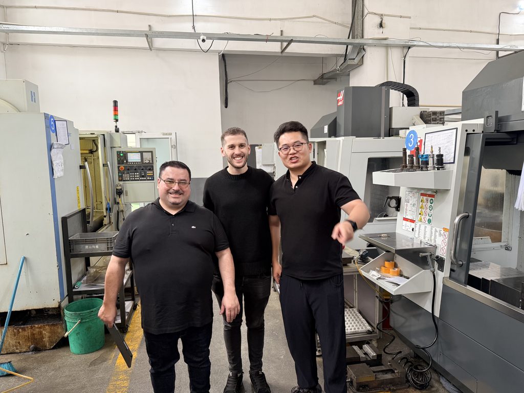 Visitors and Jinxi staff standing beside CNC machines in the workshop.